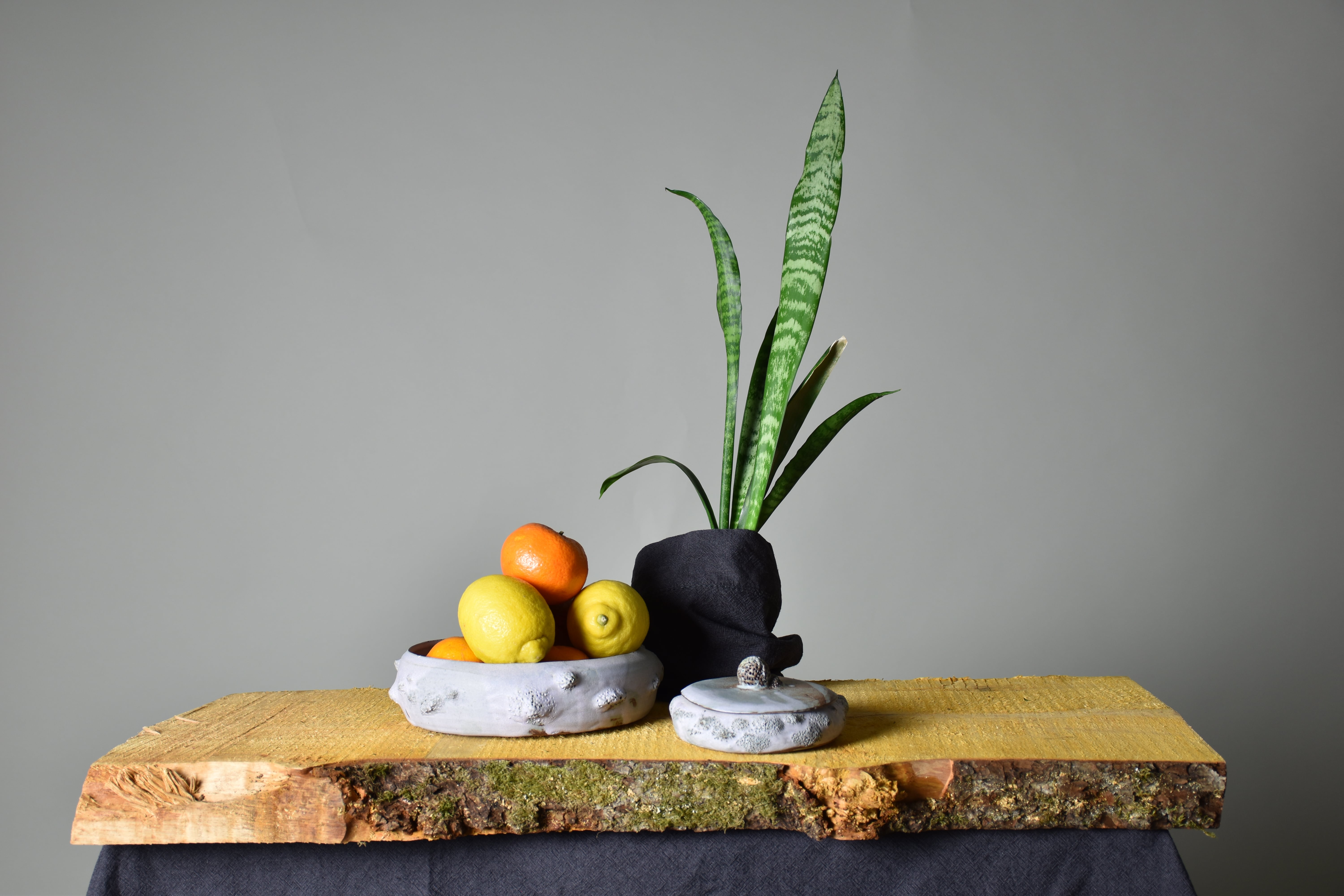 a white ceramic bowl with a lid and some fruits in it
